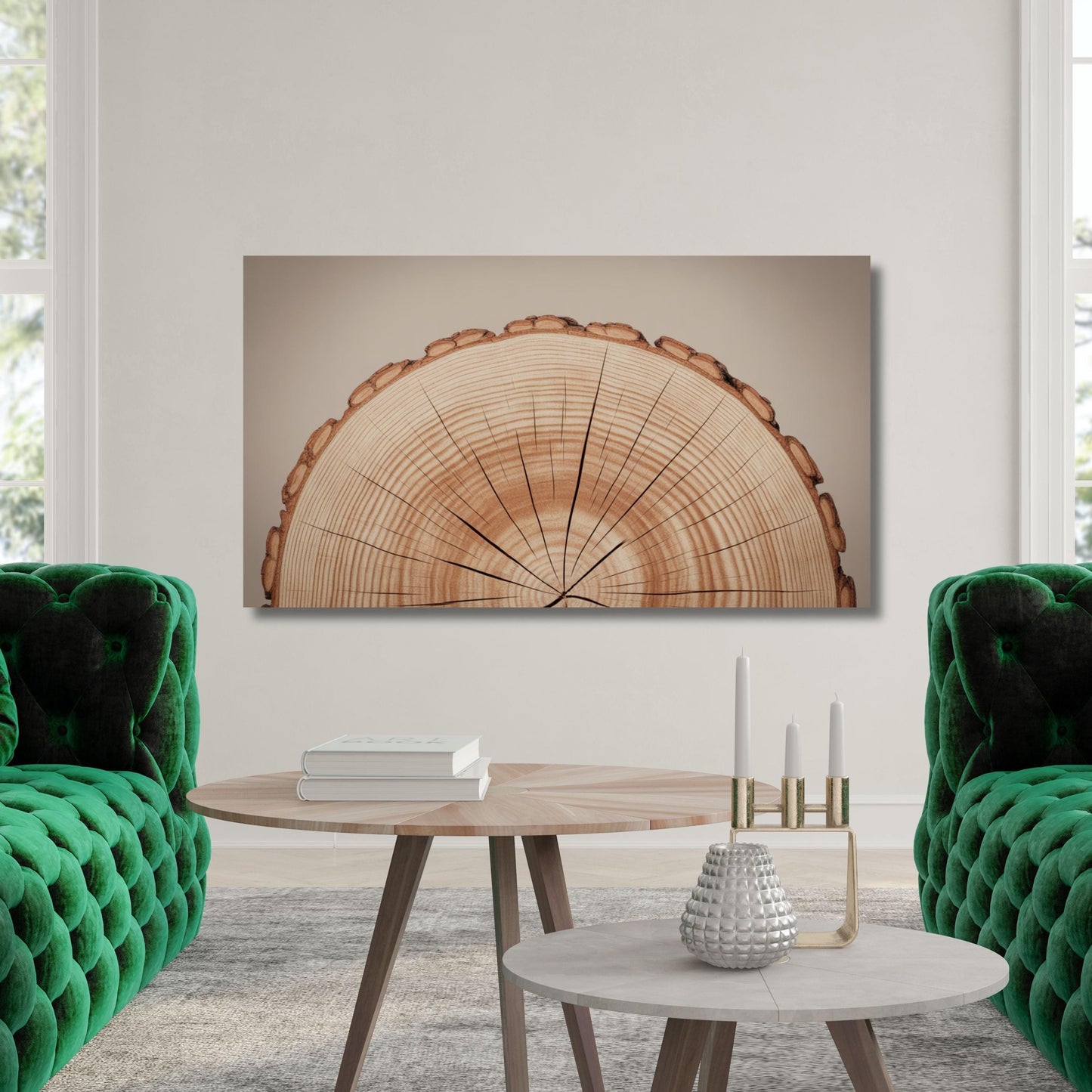 a living room with a large wooden tree stump as the focal point, hanging on the wall above a coffee table. The room is furnished with two green velvet couches and a round wooden table with a vase and candles on it.