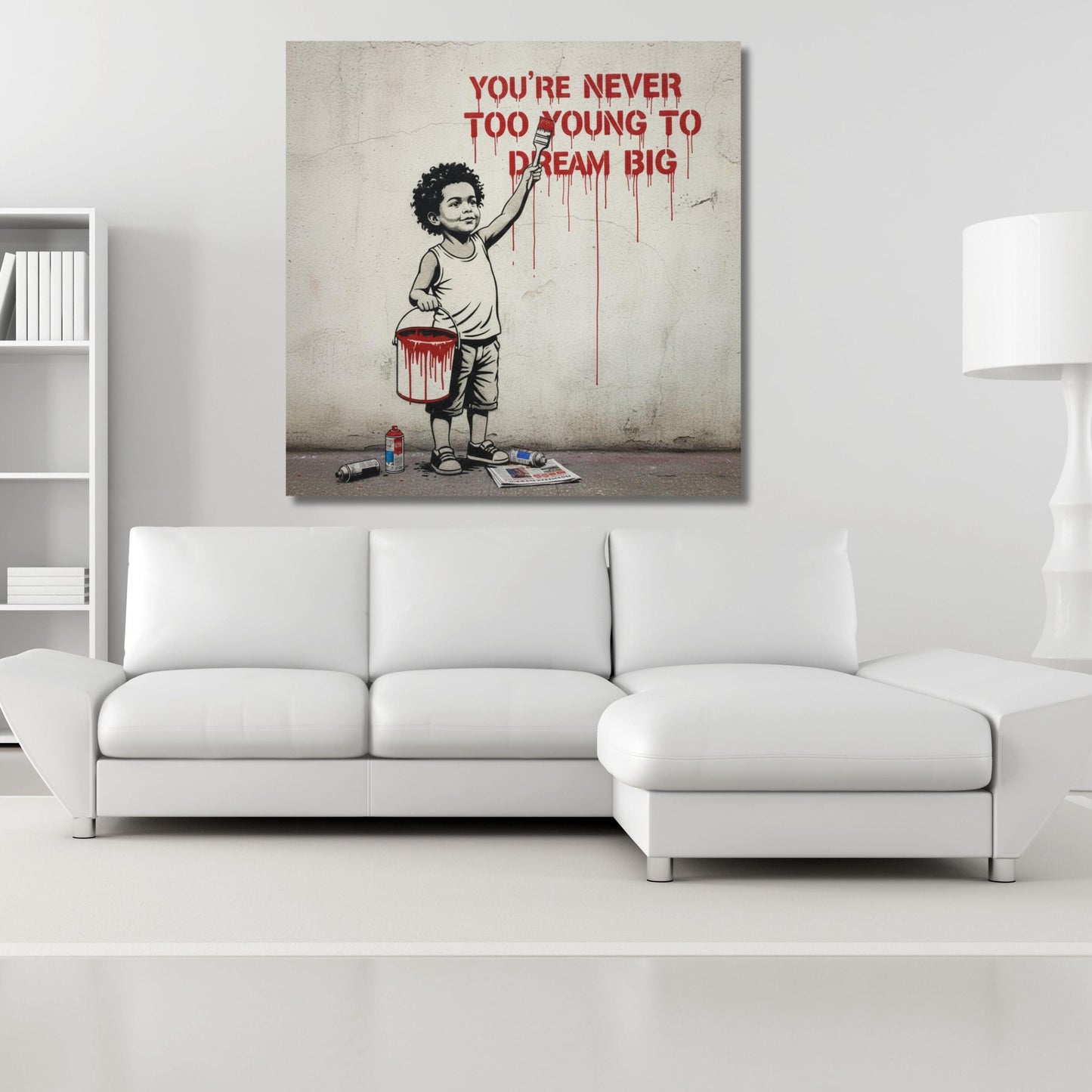 The image is a modern art piece featuring a young boy painting a wall with a bucket of paint. The text above the painting reads "YOU'RE NEVER TOO YOUNG TO DREAM BIG".