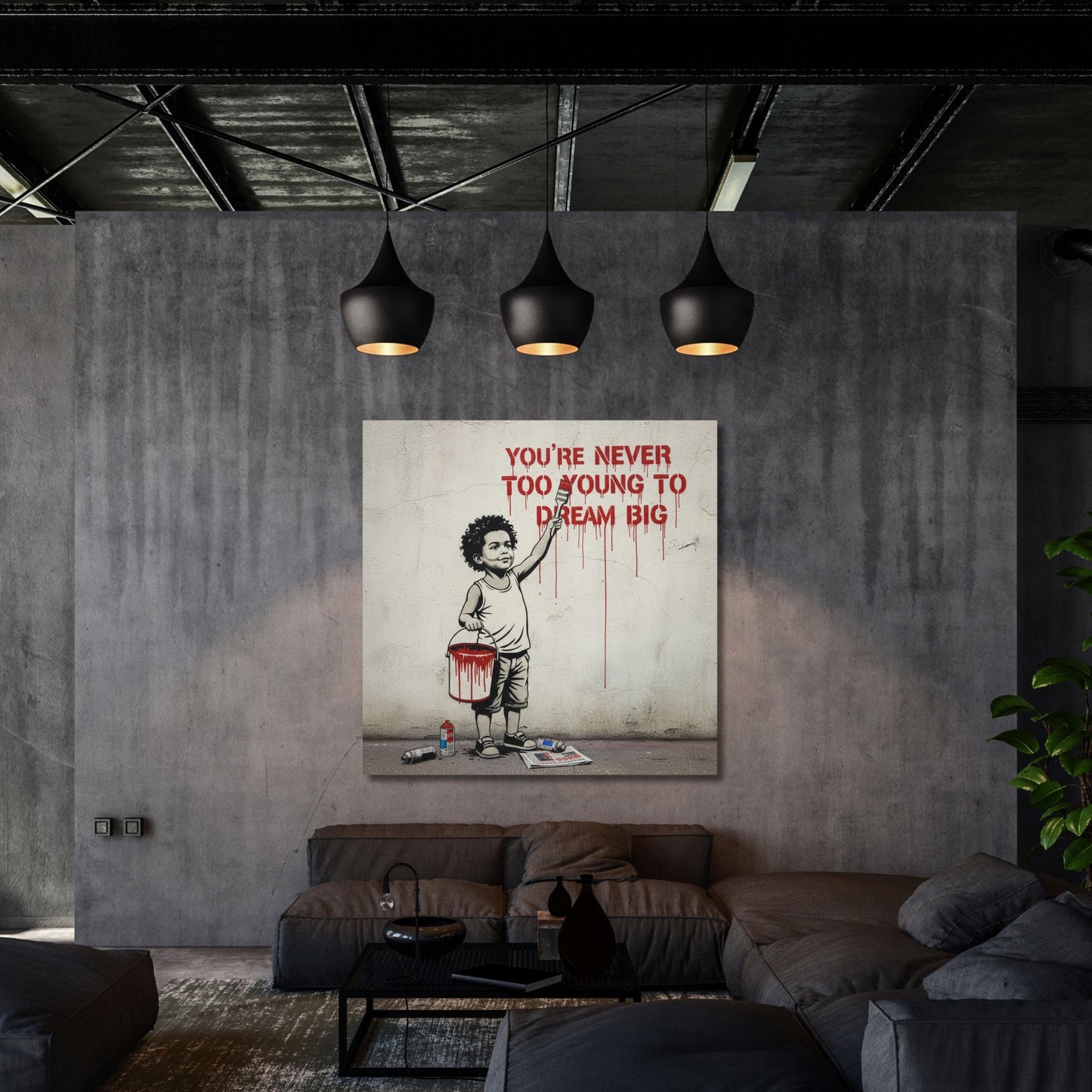 a modern living room with a large canvas print hanging on the wall. The canvas print depicts a young boy holding a paintbrush and a bucket, with the text "YOU'RE NEVER TOO YOUNG TO DREAM BIG" written above him. The room has a minimalist design with a gray wall, a black ceiling, and a black and white color scheme.
